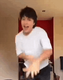 a man in a white shirt is dancing in a room with his hands outstretched .