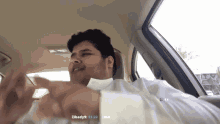 a man in a white shirt is sitting in a car with the number 13 above him