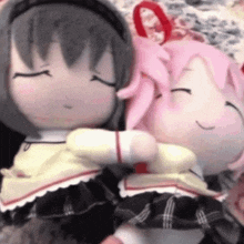 a couple of stuffed dolls are hugging each other with their eyes closed .