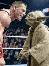 a man in a wrestling ring talks to a yoda
