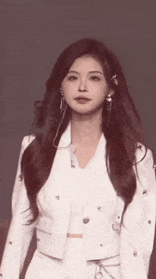 a woman with long red hair is wearing a white suit