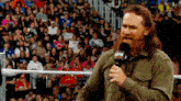 a man with a beard is standing in front of a crowd holding a microphone that says aw on it .