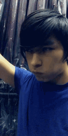 a young man in a blue shirt is making a face