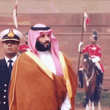 a man in a turban is standing next to a man riding a horse .