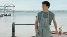a man in an apron shakes another man 's hand in front of a body of water