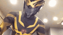 a man in a black and gold superhero costume is standing in a room with a helmet on .