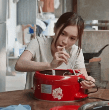 a woman is working on a red pot that has a sticker that says ' sakura ' on it