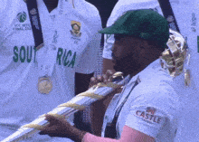 a man in a green hat holds a trophy that says south africa