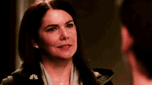 a woman is smiling and looking at a man in a dark room .