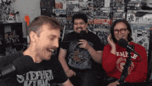 a man wearing a stephen king shirt laughs with two other men