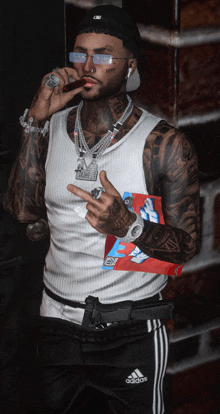 a man wearing a white tank top and black adidas pants is smoking a cigar