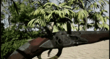 a close up of a gun with a hook on it in front of palm trees