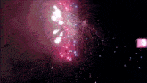 a fireworks display in the night sky with a pink light behind it