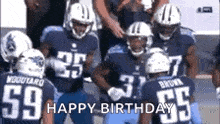 a group of football players are standing next to each other on a field and they are celebrating a birthday .