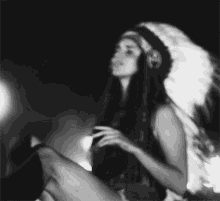 a black and white photo of a woman wearing a native american headdress and headphones