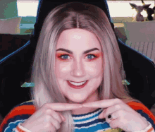 a woman in a striped sweater is smiling and making a funny face