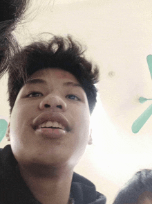 a close up of a young man 's face with a green fan in the background