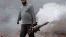 a man is holding a machine that is shooting smoke .