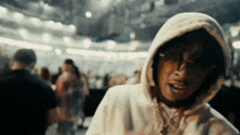 a man wearing a white hoodie and sunglasses is standing in front of a crowd .