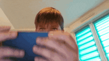 a person is holding a tablet in front of a window