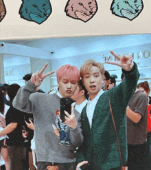 a man in a green cardigan is taking a picture of another man in a gray sweater