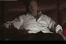 a man in a white shirt sits on a couch