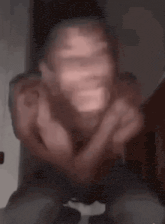 a blurry picture of a man making a funny face while sitting down .