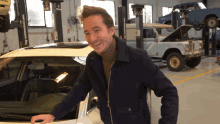 a man stands next to a white car with the hood open