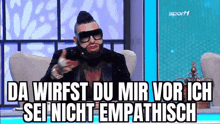 a man with a beard and sunglasses is sitting in a chair with a foreign language .