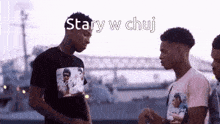 a group of young men standing next to each other with the words stary w chuj above them .