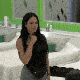 a woman in a black tank top is standing in front of two beds