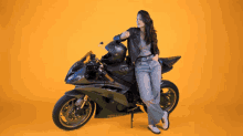 a woman leans on a motorcycle that says kawasaki on the front
