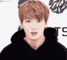 a close up of a young man wearing a black hoodie and making a funny face .