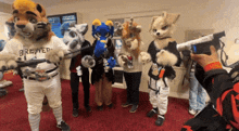 a group of furry mascots are posing for a picture and one of them is wearing a brewers shirt