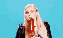 a woman is holding a red microphone in front of her face .