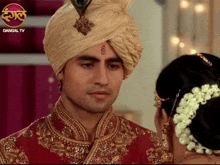 a man in a turban is looking at a woman with dangal tv on the bottom