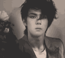 a black and white photo of a young man with messy hair and a serious look on his face .