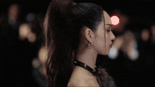 a woman with a ponytail is wearing a choker and earrings