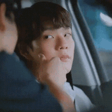 a man is putting his hand on a young boy 's face while sitting in a car .