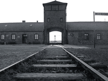 a black and white photo of a train track leading to a building with a sign that says ' l. o. '