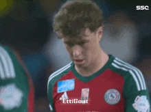 a soccer player wearing a red and green jersey with the word ettigoat on the front