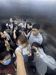 a group of people in an elevator with one wearing a mask that says ' gm ' on it