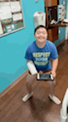 a boy in a blue shirt is holding a remote control .
