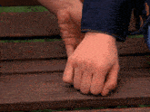 a close up of a person 's hand on a wooden bench