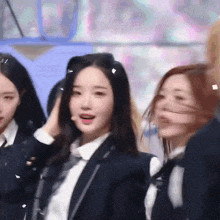a girl in a suit and tie adjusts her hair while standing next to two other girls