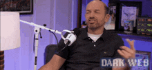 a man is sitting in front of a microphone with the words dark web on the bottom right