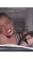 a woman is sitting in the driver 's seat of a car and laughing .