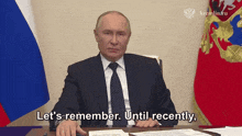 a man in a suit and tie is sitting at a desk and saying let 's remember until recently