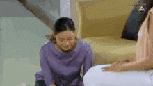 a woman in a purple shirt is kneeling down next to another woman in a white dress .