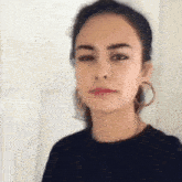 the woman is wearing hoop earrings and a black shirt .